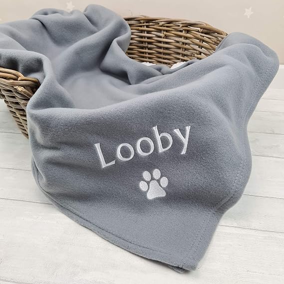 Original Crumbleberry reference photo of grey fleece pet blanket embroidered Looby with a paw print; basket is a styling prop